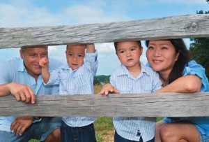 parents and two kids pose behind a fence