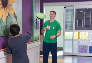 photo of nurse Dan Blair tossing a nerf football with a young patient