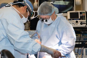 photo of nurse Dellinger in full scrubs and surgery gear, assisting in the operating room