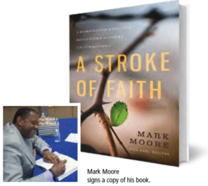 photo of Mark Moore signing his book "A Stroke of Faith"