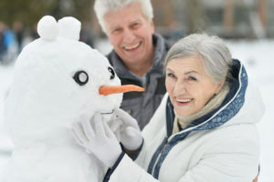 an older couple laughing with a snowman