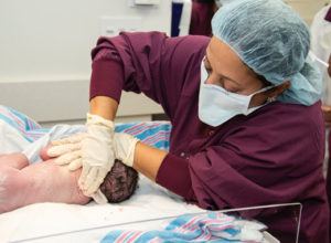 nurse swabbing a newborn baby