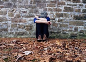 kid sitting against a wall with his head down