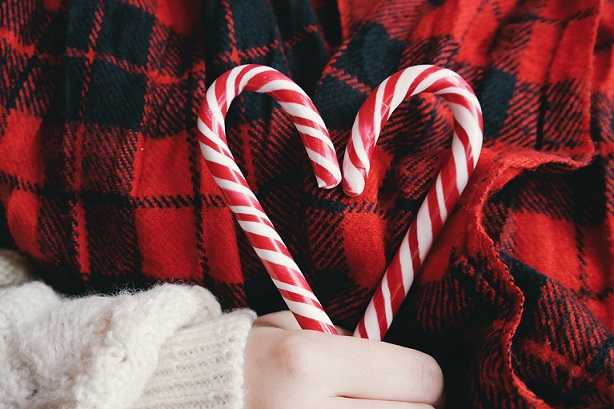 a hand holding two candy canes forming a heart shape