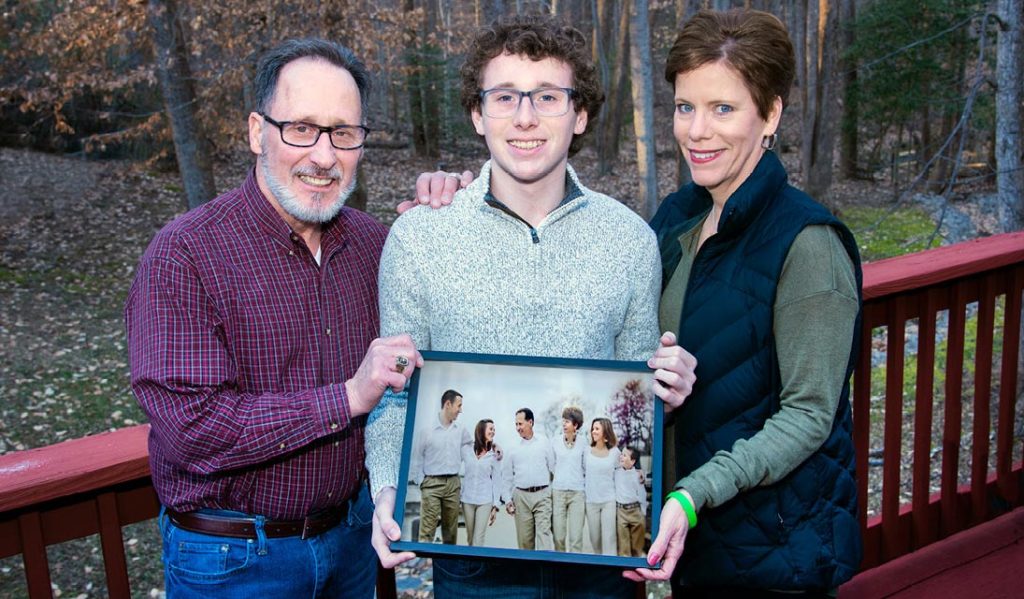 Stephen and Kelly Aldo surround their youngest child, Connor, who holds a family portrait.