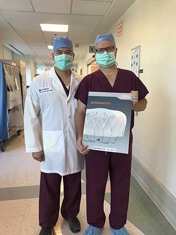 Two doctors holding a sign depicting the new Watchman FLX device