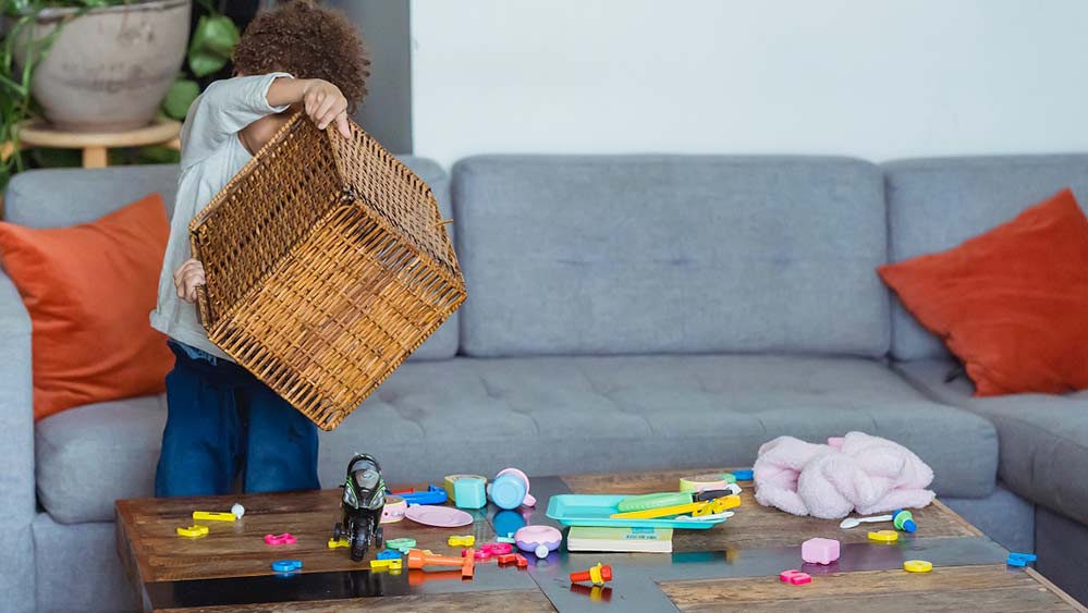 child dumping out a basket of small toys