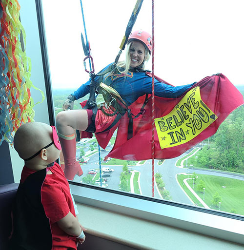 Super Girl outside window with inspiring message on her cape