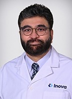 Naveed Butt, MD wearing glasses, white lab coat, navy tie and light blue button up collared shirt.